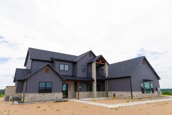 Barndominium-style custom home with a separate guest wing and staircase on North Texas acreage
